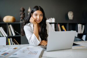 What do employers look for in a CV/resume - woman resting head on hand smiling with laptop at desk