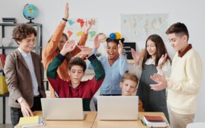free life skills lesson resources - group of students celebrating whilst two students play on a laptop